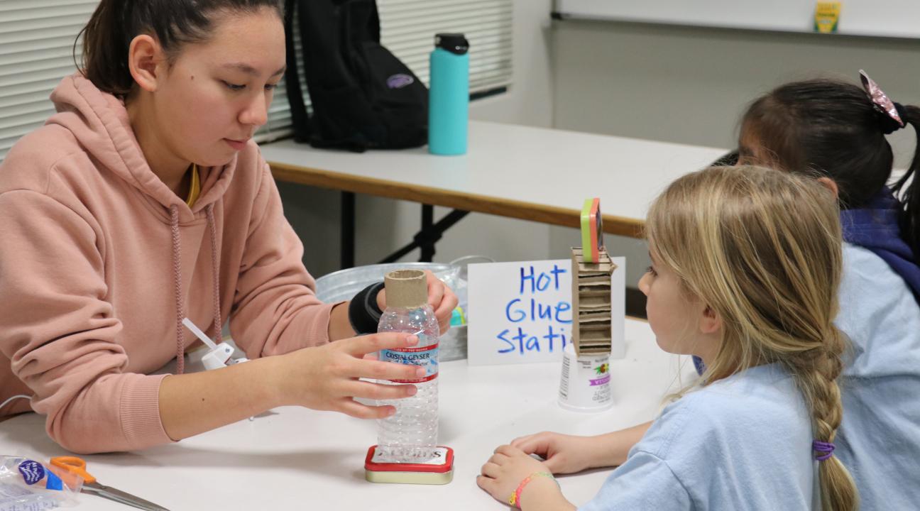 Student helping glue the recycle bots for children