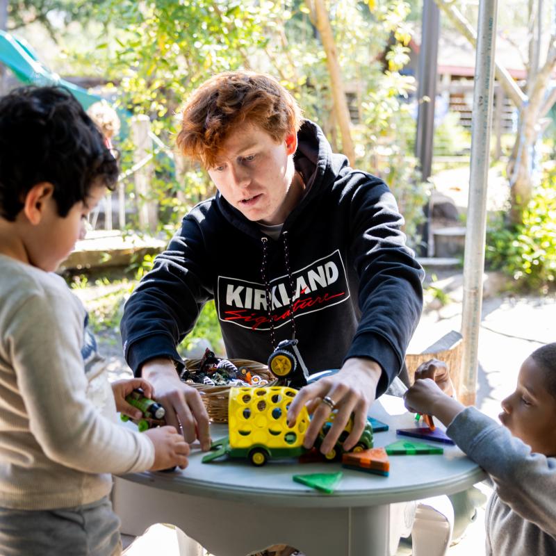 Early Childhood Professional playing with two children using car toys