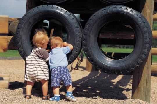 Boys looking through two hanging tires