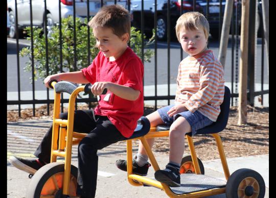 Two preschool children riding together on a bike