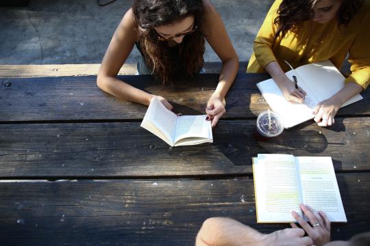 Three students sitting at table reading